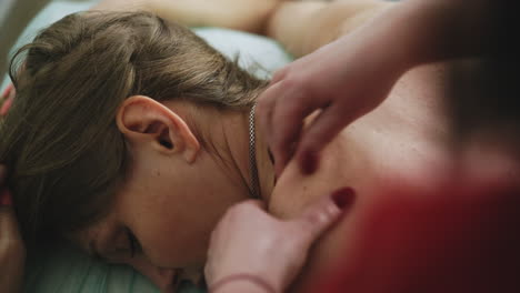 el terapeuta hace masaje en el hombro de la mujer en el sofá de la clínica.