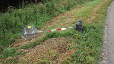 backside of circular sign with red and white caution metal post on plastic base on side of road