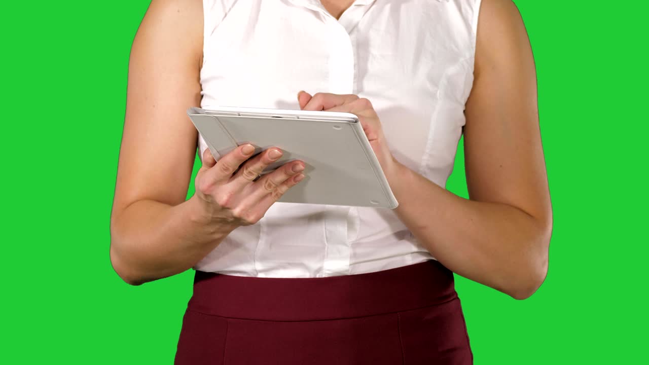 Woman holding digital tablet and using it while walking on a Green Screen, Chroma Key