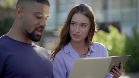 man and woman discussing something vividly on gadgets, smiling