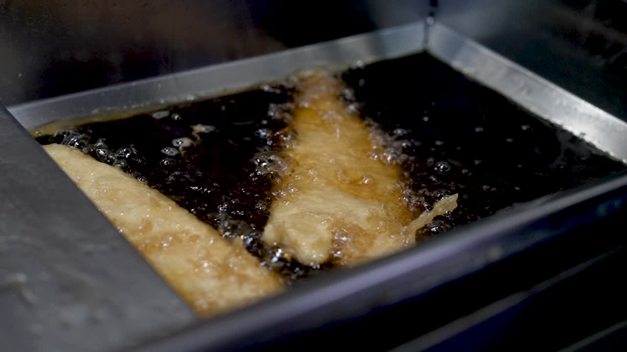 Crispy frying process of golden fish fillets in a restaurant kitchen