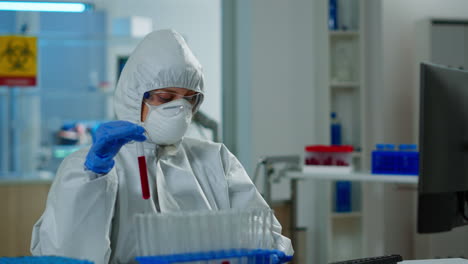 neurólogo con traje de ppe trabajando en el desarrollo de vacunas analizando muestras de sangre