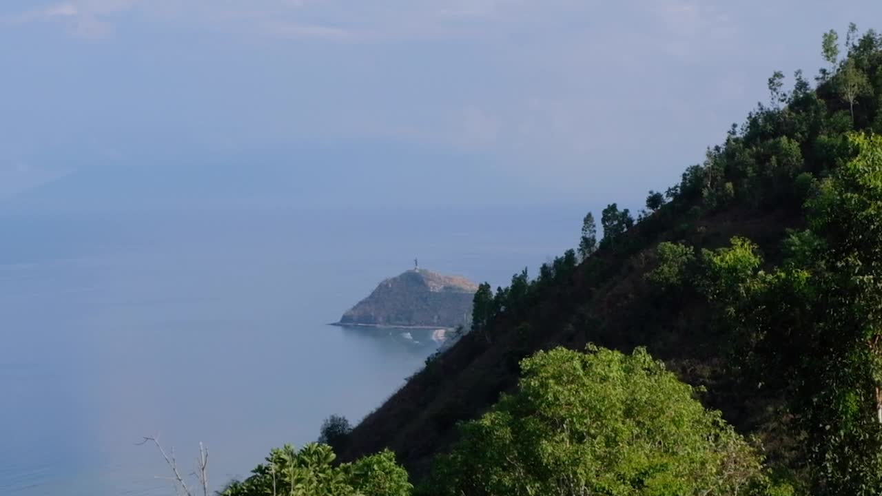 Aerial view of Cristo Rei statue in distance with ocean on tropical island in Dili, Timor-Leste, Southeast Asia