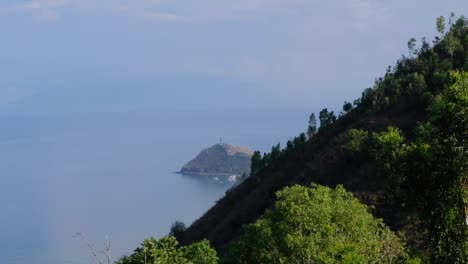 aerial view of cristo rei statue in distance with ocean on tropical island in dili, timor-leste, southeast asia