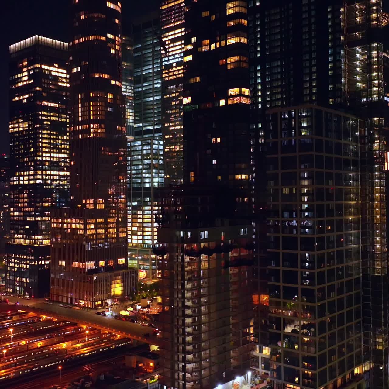 Car park and railway station at the base of beautiful high-rise buildings. Drone flying up along the modern skyscrapers
