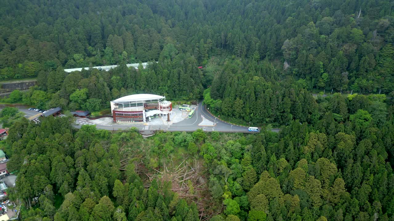Alishan national forest, showing dense green forests, roads, and a building, aerial view