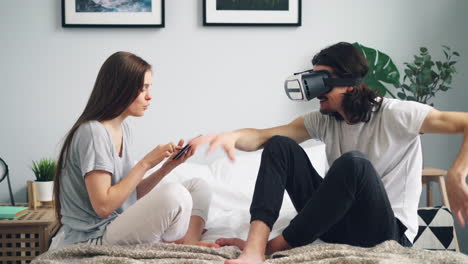 couple interacting with a vr headset and smartphone in a bedroom