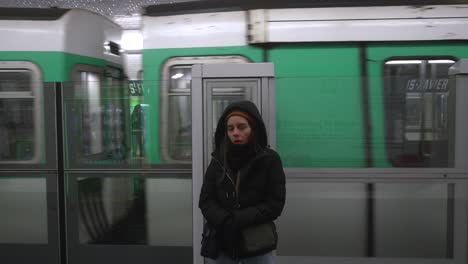 una joven linda con frío mientras espera en la parada del metro en parís.