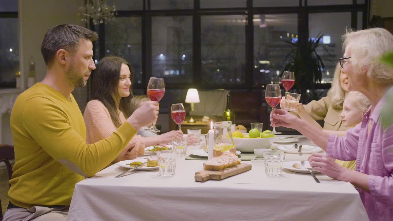 테이블에 앉아 즐거운 시간을 즐기는 저녁 식사 중 건배하는 가족의 모습