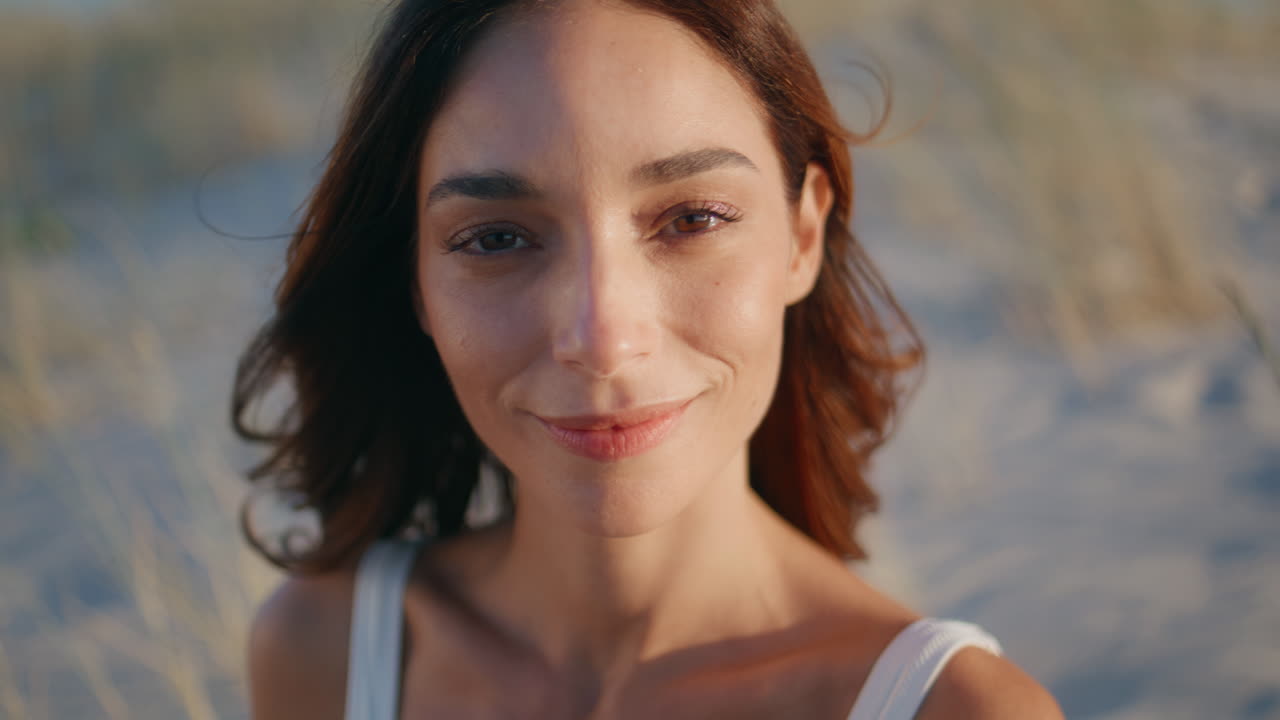 Closeup serene woman coast looking camera with soft smile. Portrait brunette