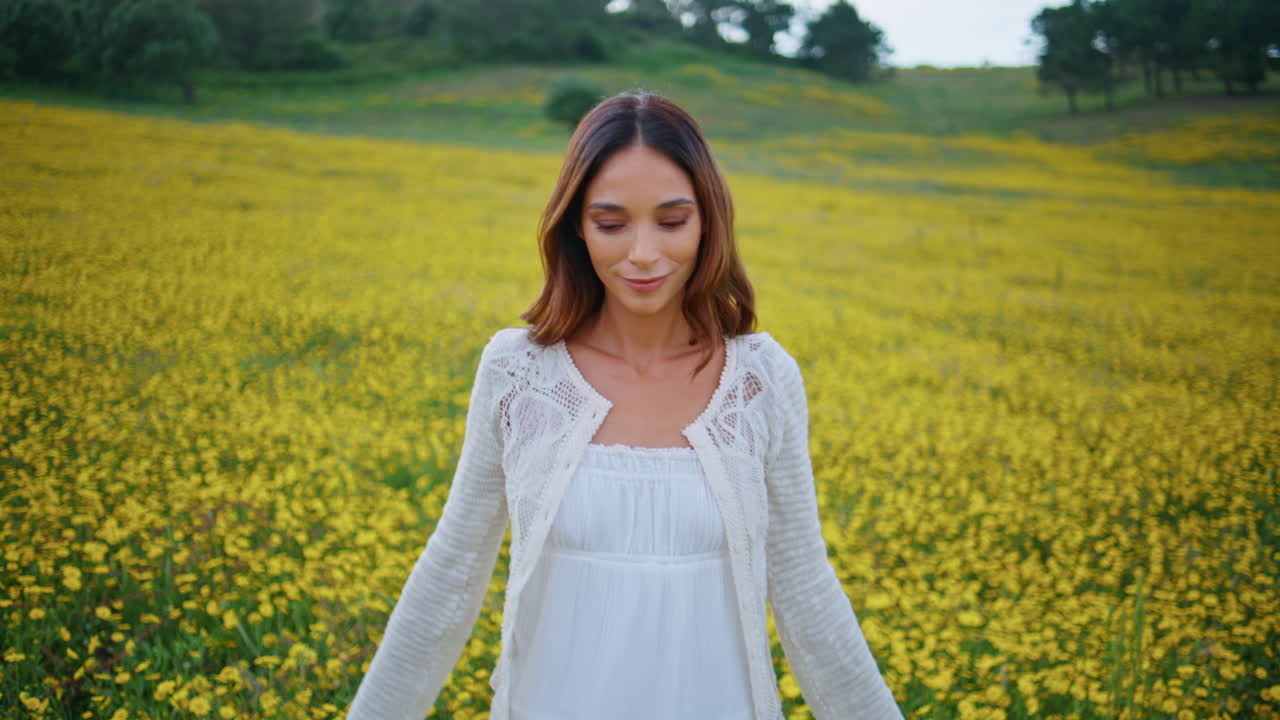 Rural girl spreading arms holding wildflower at bloomy yellow meadow closeup
