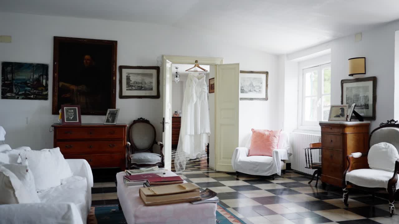 An elegant interior features vintage furniture and a wedding dress, evoking romance