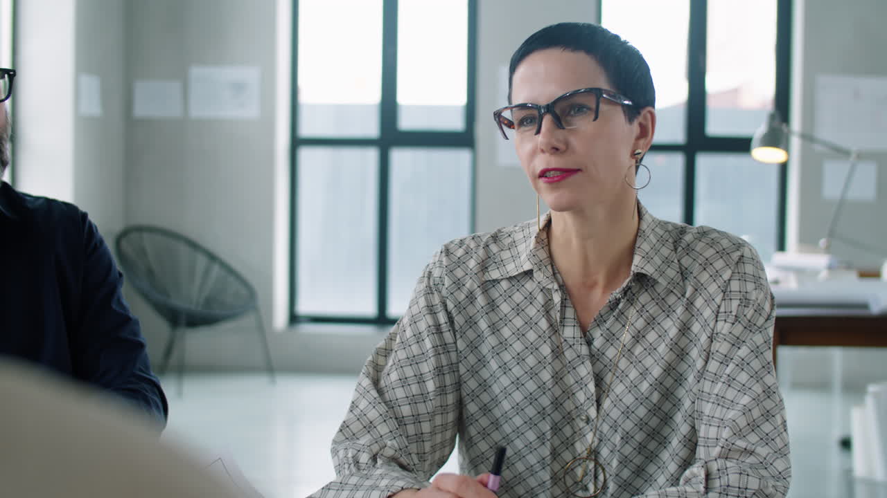 사무실 회의 에서 팀 과 대화 하는 중년 여성 건축가