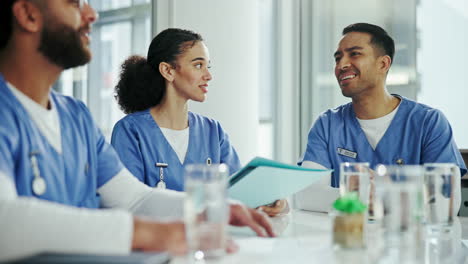 three medical professionals in blue scrubs are having a meeting in a hospital