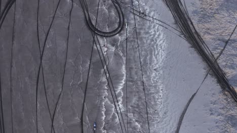 motorcross people in bikes extreme driving on volcanic black beach, top down, tire tracks