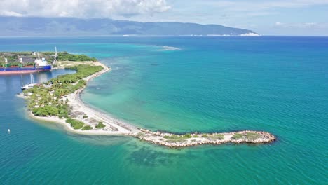 Toma-Aérea-De-Bahia-De-Neiba-Con-Mar-Caribe-Cristalino-Y-Barco-De-Contenedores-De-Atraque-En-La-Bahía