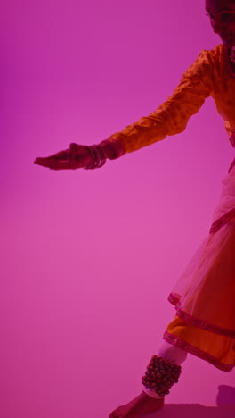 video de estudio vertical de una bailarina de kathak que realiza un baile vestida con el vestido tradicional indio contra un fondo púrpura 4