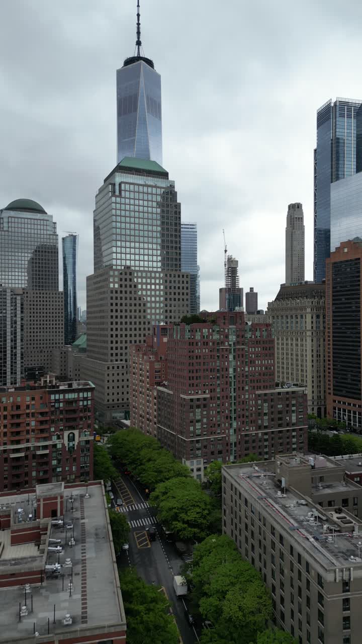 Vertical drone footage rising high over S End Ave., New York, offering a stunning aerial view of skyscrapers, streets, and the waterfront in an urban setting.
