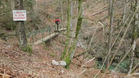 Man-walking-over-a-bridge-with-fall-colour-leaves-on-the-ground