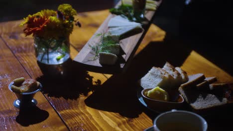 cheese board being placed onto table of food with bread and food, mid shot