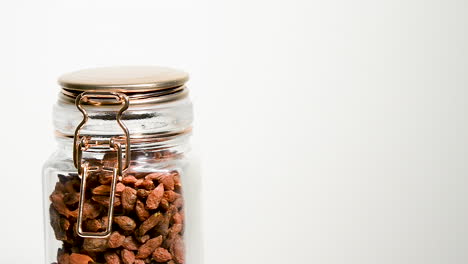 A-jar-of-dried-goji-berries-rotates-slowly-against-a-white-background