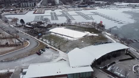 drone volando hacia una pista de hockey en el borde de un puerto congelado de hamilton en el lago ontario