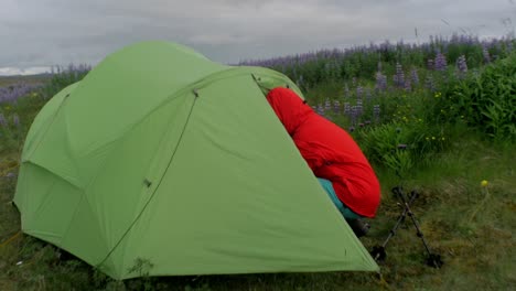 wild camping on iceland, hiker leaving a green tent pitched in a volcanic landscape, camera movement, camera tracking dolly in on a steadicam gimbal stabiliser, wide angle shot