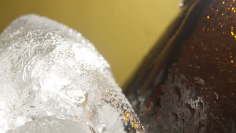 cerca de las gotas de condensación que corren por botellas de vidrio de cerveza fría o bebida gaseosa que se enfrían en un cubo lleno de hielo contra un fondo amarillo 3