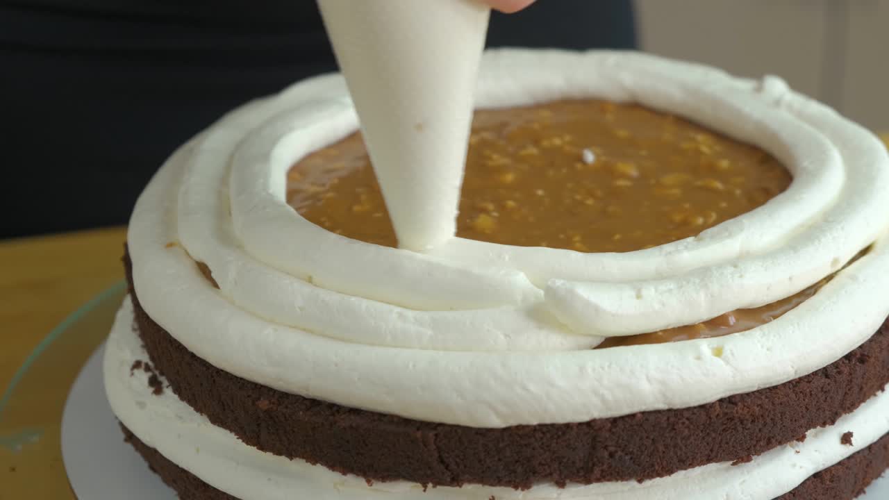 크림과 비스으로 달한 케이크를 만드는 여성 손의 클로즈업.