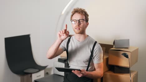 a handsome young man counts parcels and writes everything down on a tablet