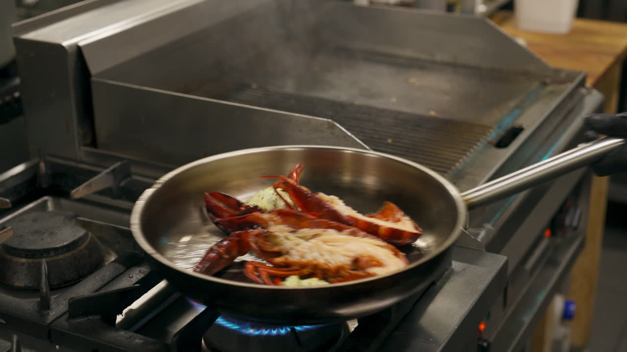 Lægger grillet hummer i panden til tilberedning i restaurantkøkken. Nærbillede