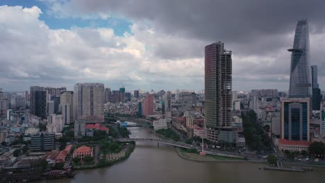 Luftschwenkaufnahme-Von-Saigon-Von-Ho-Chi-Minh-Stadt-über-Die-Skyline-Bis-Zum-Flusshafen-Mit-Marineschiffen-Und-Touristenbooten