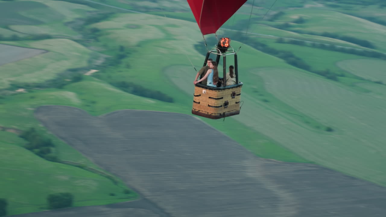 close up of hot air balloon basket holding passenger as pilot increases burner flame to ascend over green fields under dusky sky capturing thrilling aerial journey