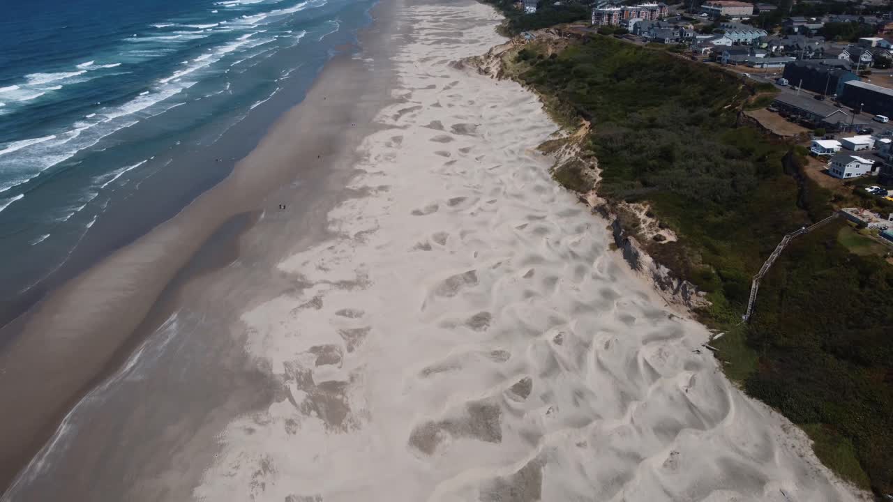 toma de drones que muestra las verdes colinas de newport, las dunas de arena de la playa de nye y el poderoso océano pacífico en la costa de oregón