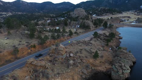 cars on mountain valley road by lake aerial reveal shot 4k