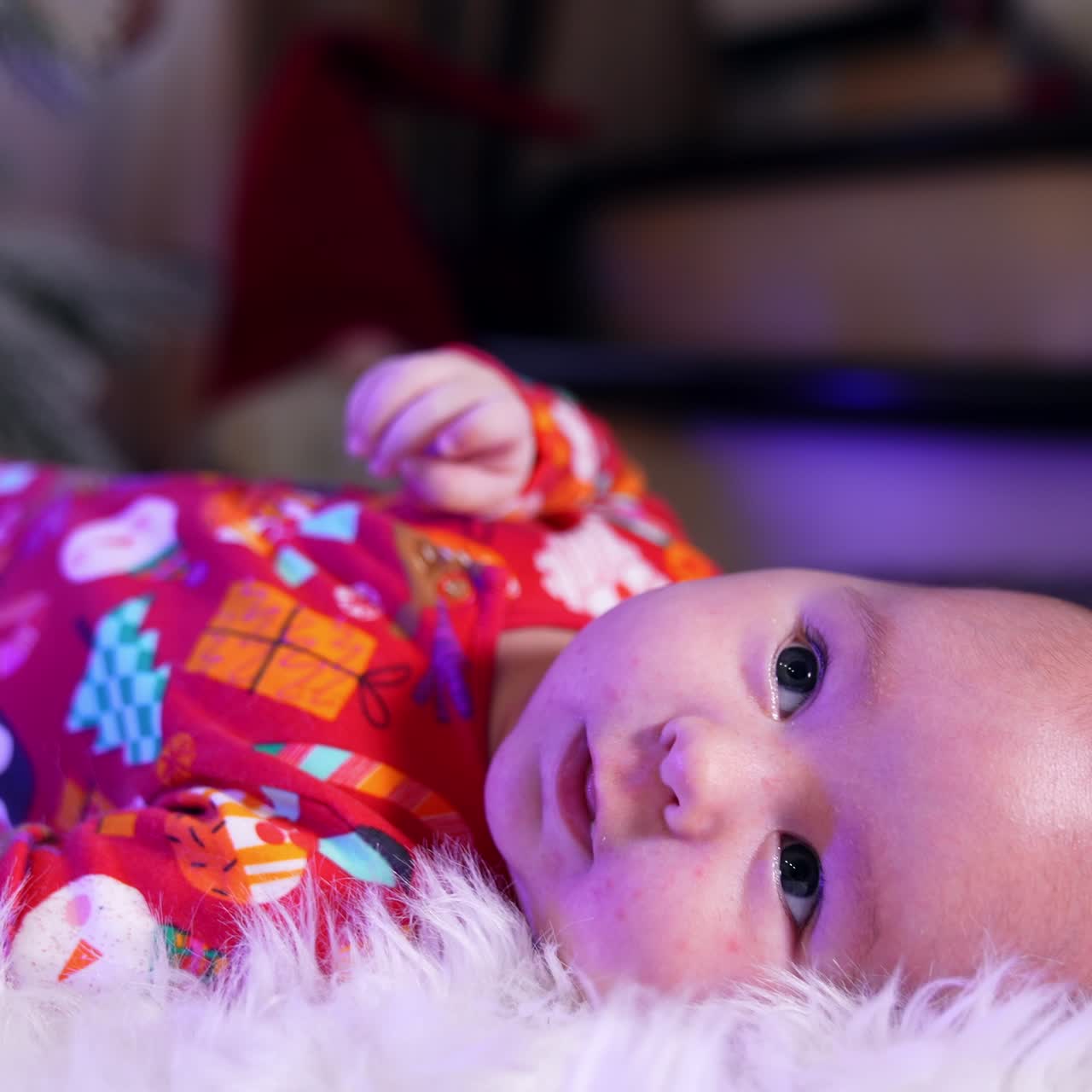 Cheerful smiling baby lies on his back tossing his arms and legs. Adorable healthy little child close up. Blurred backdrop