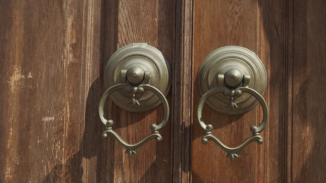 Udsmykkede metaldørhammere på en antik trædør
