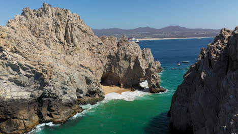 drone shot of el arco and sea cliffs and people in boats in cabo san lucas mexico, rotating