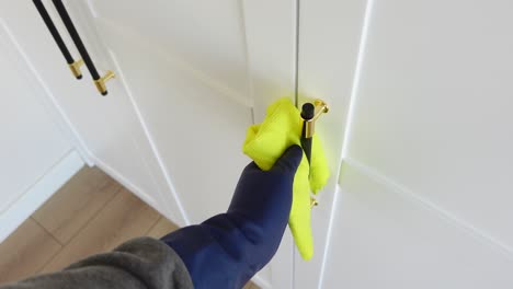 cleaning door handles with a green cloth and blue gloves