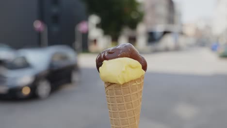 Fokussierte-Nahaufnahme-Einer-Waffel-Mit-Vanille--Und-Schokoladeneis,-Die-Von-Einer-Person-Auf-Der-Straße-Gedreht-Wird