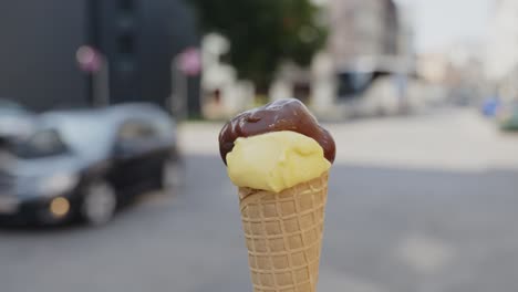 primer plano enfocado de un cono de helado de vainilla y chocolate que una persona hace girar en la calle