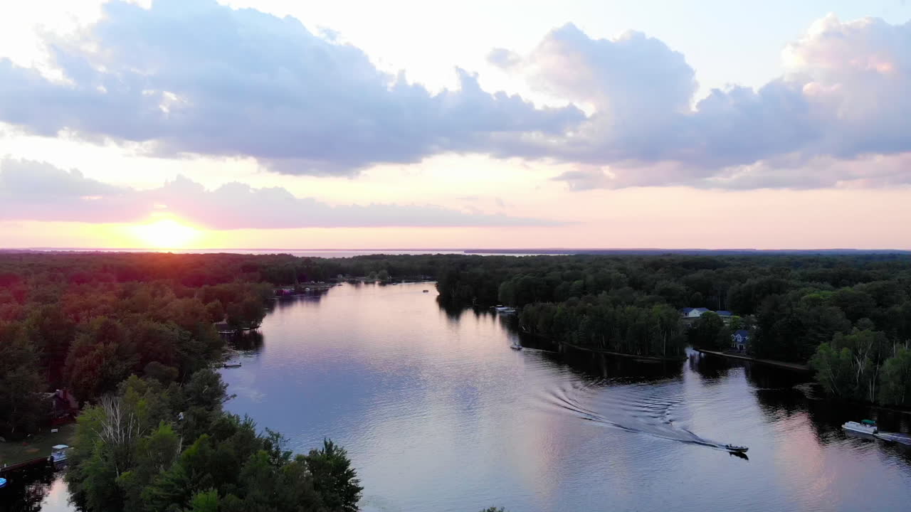 Ripresa ascendente con drone di un tramonto su un piccolo lago nel Michigan durante l'estate.