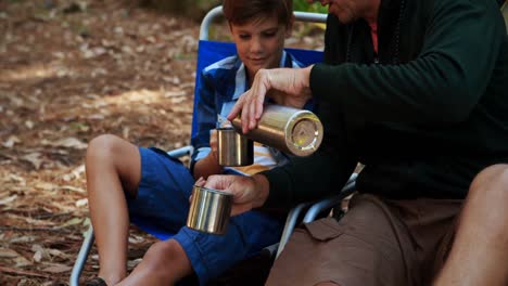 father and son having coffee outside tent