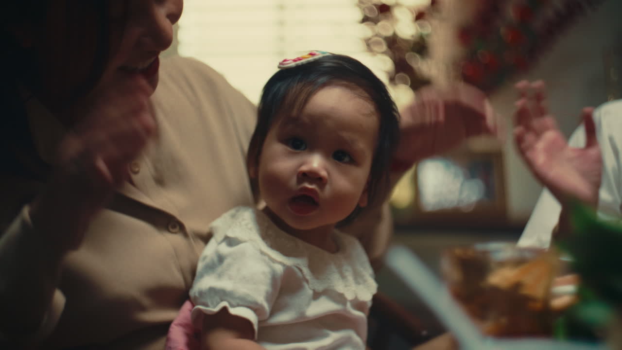 A mother holds her baby at a family dinner table, with warm and joyful emotions