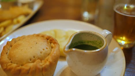 Pie-and-mash-with-gravy,-green-vegetables-and-a-pint-of-ale