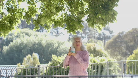 Happy-senior-biracial-woman-drinking-coffee-at-balcony-at-home,-slow-motion