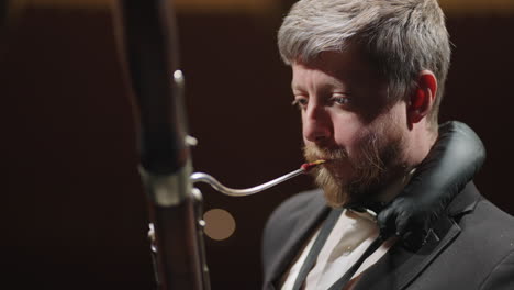 classic musician is playing bassoon in rehearsal or concert of symphonic orchestra closeup