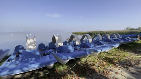 Panning-wide-angle-shot-of-paddle-boats-at-the-shore-of-Lake-Balaton-during-off-season,-Balatonfenyves,-Hungary