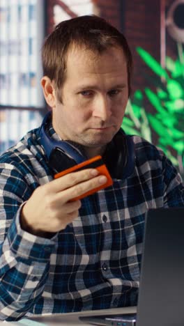 Vertical video Man doing internet shopping, carefully typing credit card information