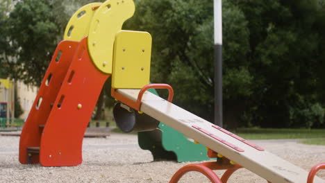 Close-up-view-of-an-empty-wooden-seesaw-in-a-park-on-a-windy-day